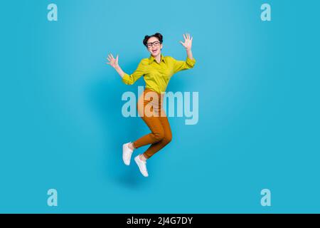 Photo pleine longueur d'une personne folle et gaie sautant les bras isolés sur fond bleu Banque D'Images