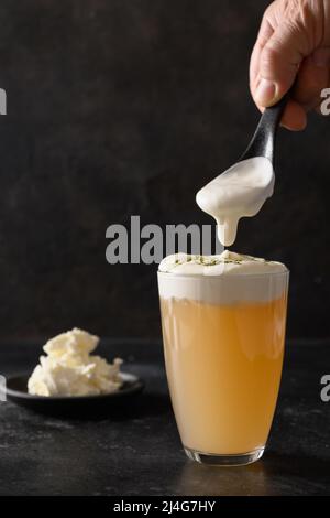 Boisson chinoise asiatique thé au fromage en verre avec une couche de mousse de fromage à la crème fouettée surmontée sur fond noir. Format vertical. Banque D'Images