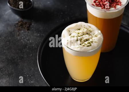 Thé au fromage dans des verres à base de thé vert et de thé noir avec mousse de fromage à la crème fouettée sur fond noir. Copier l'espace. Gros plan. Banque D'Images