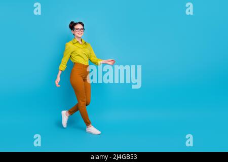 Photo pleine longueur de jeune personne joyeuse marchant espace vide isolé sur fond bleu Banque D'Images