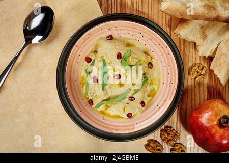 Poulet satsivi à la sauce aux noix, garni de légumes verts et de graines de grenade Banque D'Images