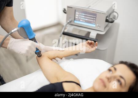 Le médecin applique un traitement par onde de choc sur le genou des femmes Banque D'Images