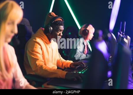 Joueur professionnel de cybersport portant des écouteurs se concentrant sur le jeu avec les membres de l'équipe tout en jouant à un jeu vidéo en ligne. Le tournoi eSport concep. Photo de haute qualité Banque D'Images