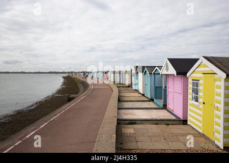 La promenade sur le front de mer à Brightlingsea, Essex, avec une rangée de cabanes de plage colorées en arrière-plan. Banque D'Images