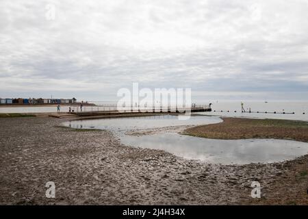 Une vue sur le paysage à travers les bassins d'eau et de boue à Brightlingsea, Essex, sur la rivière Colne. Des cabanes de plage à distance. Banque D'Images