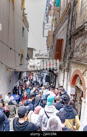 Casbah, Alger : des gens bondés attendent dans la file pour des sardines de poissons grillés et du foie d'agneau dans un restaurant sauce. Vue en angle bas depuis l'arrière de la foule. Banque D'Images