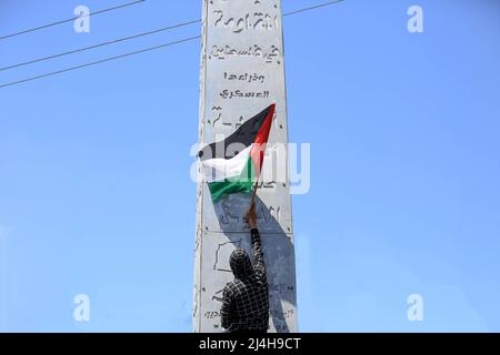 Gaza, Palestine. 15th avril 2022. Un homme palestinien lève le drapeau palestinien alors qu'il participe à une manifestation de solidarité avec les fidèles de la mosquée Al-Aqsa à Khan Yunis, dans le sud de la bande de Gaza. Des affrontements ont éclaté entre les forces de sécurité israéliennes et les Palestiniens de Jérusalem (adorateurs de la mosquée Al-Aqsa), à la lumière de l'escalade des tensions ces dernières semaines en Cisjordanie et à Jérusalem. Crédit : SOPA Images Limited/Alamy Live News Banque D'Images