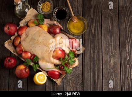 Jeunes canards entiers crus bio sur papier froissé avec sel et pommes rouges de jardinage sur fond de texture noire. Avec lindre mariné Banque D'Images