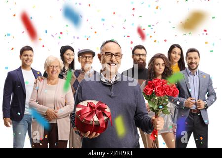 Homme mature tenant des roses rouges et une boîte cadeau avec la famille et les amis derrière isolé sur fond blanc Banque D'Images