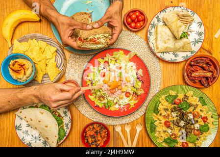 Plats et hors-d'œuvre de restauration rapide italiens et mexicains, salade de pâtes, burrito farci, houmous aux chips de tortilla, sandwich aux légumes, nourriture pour les mains Banque D'Images