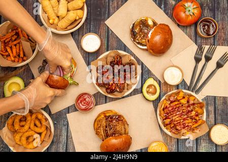 Les mains du chef préparent des plats de restauration rapide, tequeños, hamburgers assortis, pommes de terre avec sauces, rondelles d'oignon, patates douces frites Banque D'Images