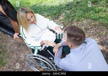 Une femme en fauteuil roulant communique avec un homme dans le parc Banque D'Images