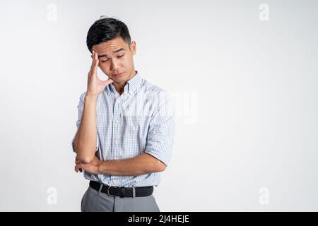 Le jeune homme asiatique stressé tient la tête Banque D'Images
