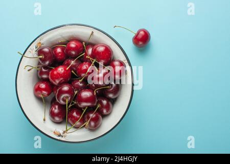 Cerises douces dans un bol, sur fond bleu Banque D'Images