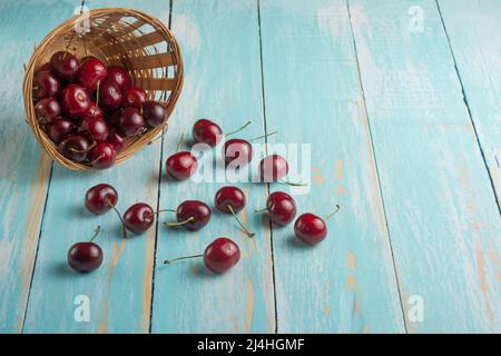 Panier de cerises douces contre l'arbre bleu avec espace vide pour l'inscription Banque D'Images