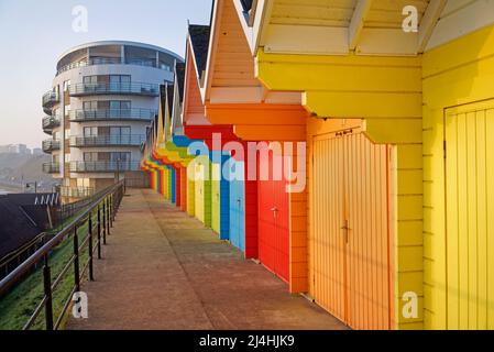 Royaume-Uni, North Yorkshire, Scarborough, les Chalets de plage colorés et le Sands Holiday Apartment Building au-dessus de North Bay Promenade. Banque D'Images