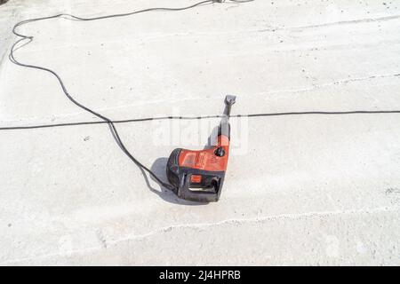 perceuse à percussion avec un burin plat à buse repose sur la surface en béton du plafond, mise au point sélective Banque D'Images