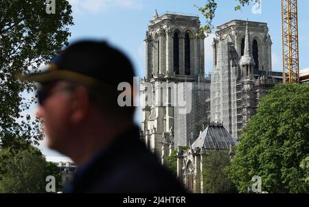 Paris, France. 15th avril 2022. Un homme marche près de la cathédrale notre-Dame en cours de rénovation à Paris, France, le 15 avril 2022. Le 15 avril 2019, un énorme incendie a éclaté dans la cathédrale historique située au coeur de Paris et a détruit la flèche du bâtiment. Quelques heures après l'incendie, le président français Emmanuel Macron a promis que la cathédrale, l'un des plus beaux exemples de l'architecture gothique française, serait reconstruite et rouverte d'ici 2024. Credit: Gao Jing/Xinhua/Alamy Live News Banque D'Images