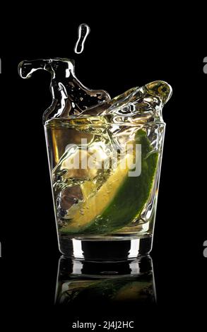 tequila dorée avec tranche de lime et éclaboussures Banque D'Images
