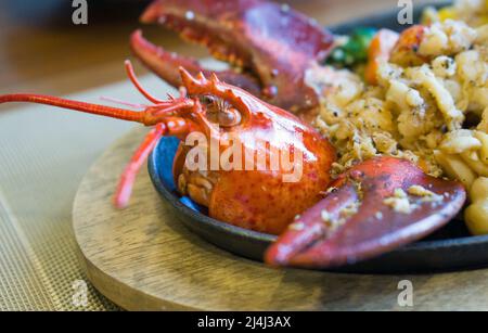 Steak de homard de style japonais servi sur une poêle chaude avec des légumes beurrés comme accompagnement. Banque D'Images