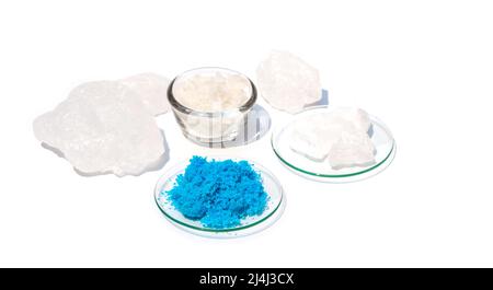 Gros plan sur une table de laboratoire blanche. Sulfate de cuivre(II) dans le verre de surveillance chimique. Le cristal d'alun et le sel de Flake ont été placés plus loin Banque D'Images