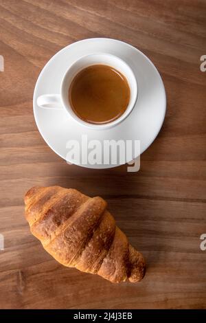 Croissant avec espresso dans une tasse blanche, vue de dessus Banque D'Images