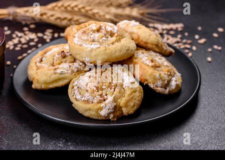 Feuilleté feuilleté frais fait maison aux petits pains à la cannelle avec crème anglaise et raisins secs sur fond de vieux béton foncé Banque D'Images