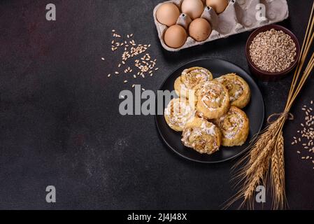 Feuilleté feuilleté frais fait maison aux petits pains à la cannelle avec crème anglaise et raisins secs sur fond de vieux béton foncé Banque D'Images