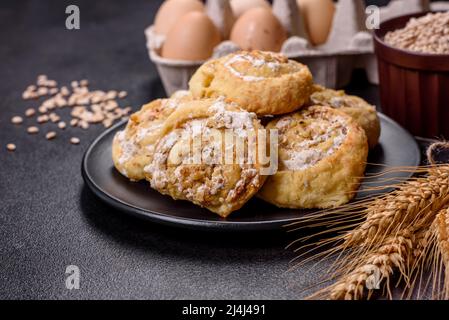 Feuilleté feuilleté frais fait maison aux petits pains à la cannelle avec crème anglaise et raisins secs sur fond de vieux béton foncé Banque D'Images