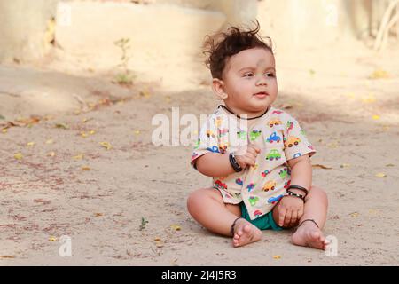 Gros plan d'une photo portrait d'Un petit nouveau-né mignon bébé hindou assis sur le sol à l'extérieur avec visage souriant, inde Banque D'Images