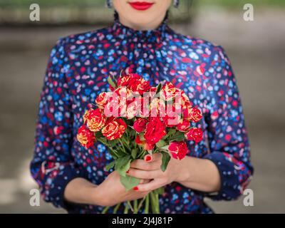 Femme élégante et méconnaissable portant un bouquet de roses rouges Banque D'Images