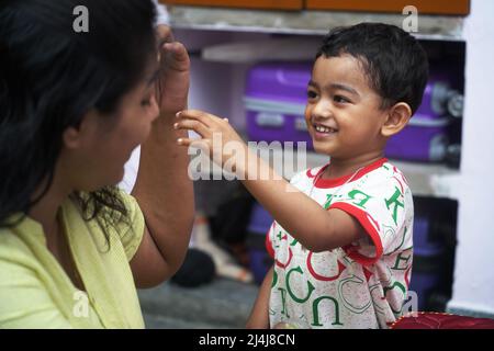 un jeune garçon donnant un sourire à sa mère et en allant vers l'extérieur pour toucher sa mère avec la main. Banque D'Images