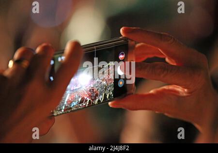 femme prend un film avec un smartphone lors d'un concert avec de nombreux spectateurs Banque D'Images