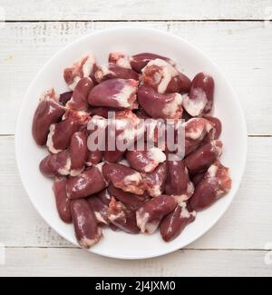 Vue de dessus des coeurs de poulet dans un bol sur une table en bois Banque D'Images