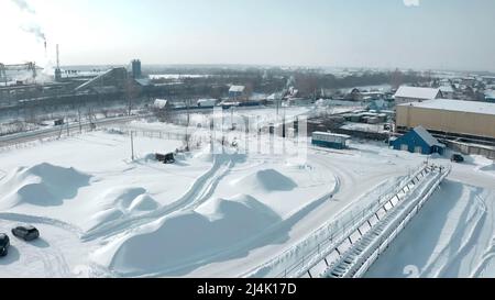 Vue panoramique en hiver. Attache. Une grande grue en production se trouve à côté de la ville et de la route sur laquelle les voitures circulent Banque D'Images