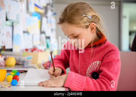 Dnipro, Ukraine - 04 avril 2022 : une petite fille dessine une photo dans un centre de secours aux réfugiés de Dnipro. Banque D'Images