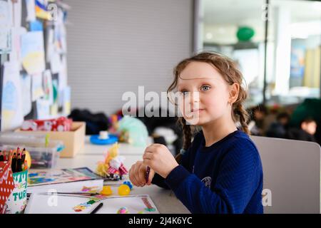 Dnipro, Ukraine - 04 avril 2022 : une petite fille dessine une photo dans un centre de secours aux réfugiés de Dnipro. Banque D'Images