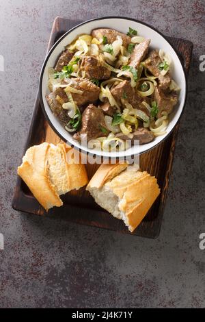 de délicieux morceaux de foie de veau sautés et cuits avec des rondelles d'oignon dans le bol de la table. Vue verticale du dessus Banque D'Images