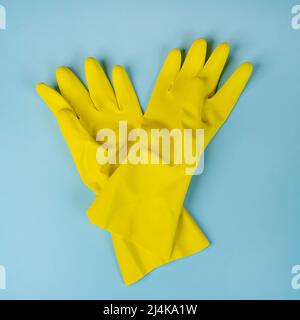 deux gants de nettoyage en caoutchouc jaune. sur une surface bleue Banque D'Images