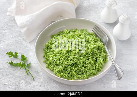 Riz végétalien à l'huile verte dans un bol blanc sur fond gris, espace libre. Délicieux aliments sains faits maison Banque D'Images