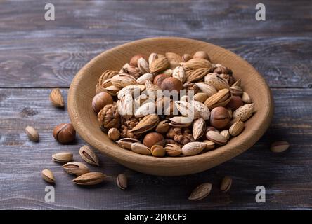 Variété de noix dans un bol en bois sur une table en bois. Amandes, noix, noisettes, pistaches. Style rustique. Horizontal Banque D'Images