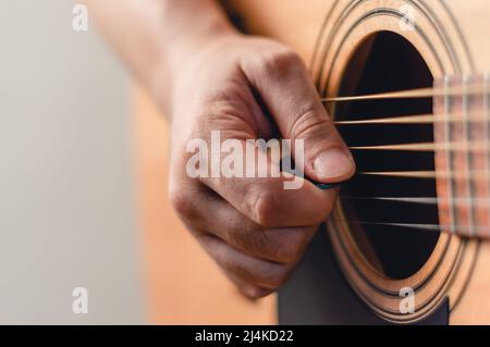 gros plan main mâle caucasienne avec un plectrum jouant de la guitare acoustique avec des cordes d'acier, concept de musique, espace de copie sur la gauche. Banque D'Images