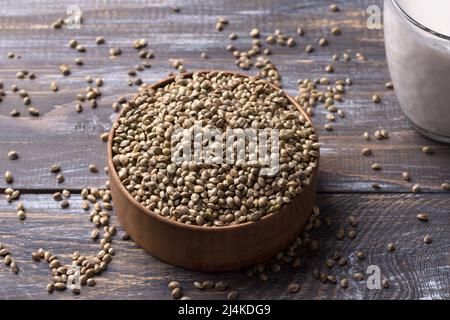 Graines de chanvre dans un bol en bois et lait de chanvre sur fond en bois. Superalimentation, nourriture naturelle saine végétalienne Banque D'Images