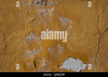 Le plâtre ocre jaune s'écaille du mur abîmé. Vieux mur sale de plâtre de peeling avec des flocons de plâtre tombant. Arrière-plan abstrait avec copie Banque D'Images