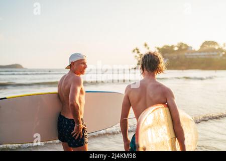 Adolescent avec surf aller à la mer pour le surf avec le père sur l'île Sri Lanka. Ils ont des vacances d'hiver et profiter d'une belle lumière de coucher de soleil Banque D'Images