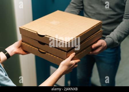 Gros plan de la cliente recevant des boîtes en carton avec des plats à emporter à la maison des mains du liveur. Banque D'Images