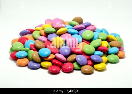 Gros plan sur une pile de friandises au chocolat multicolores et aux motifs croustillants, isolées sur un fond blanc. Banque D'Images