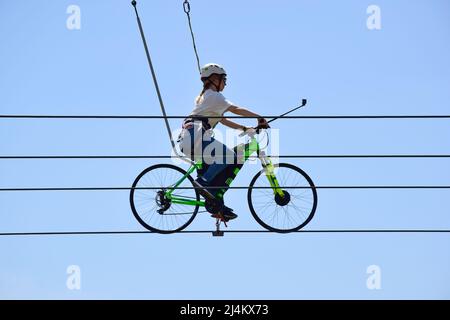 Une jeune femme fait une balade à vélo sur des cordes au-dessus du sol. Contre le ciel bleu Banque D'Images