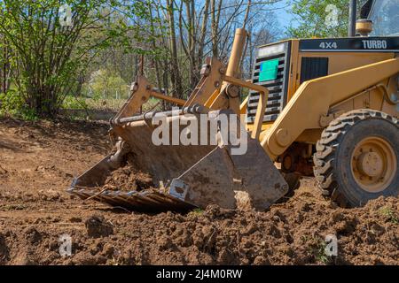 Défrichement et nivellement d'un terrain privé. Pelle hydraulique jaune qui fait de la terre dans un godet large Banque D'Images