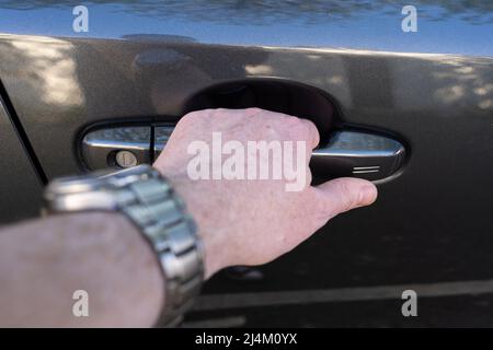 Gros plan de la main d'un homme tenant une poignée de porte de voiture et déverrouillant la voiture en appuyant sur le bouton sans clé d'une Toytota CH-R hybride 2021. ROYAUME-UNI Banque D'Images